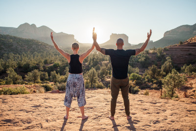 Two people on a mountain top doing yoga in the sunshine